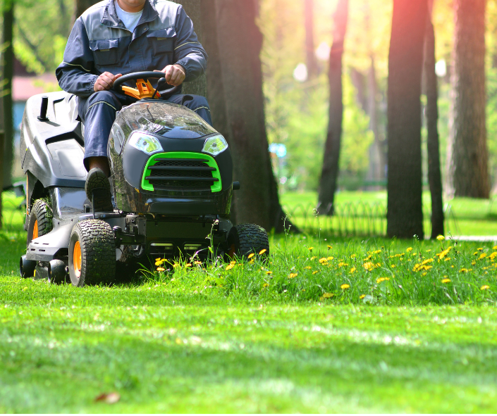 A riding lawn mower on a large, well-kept property with trees.